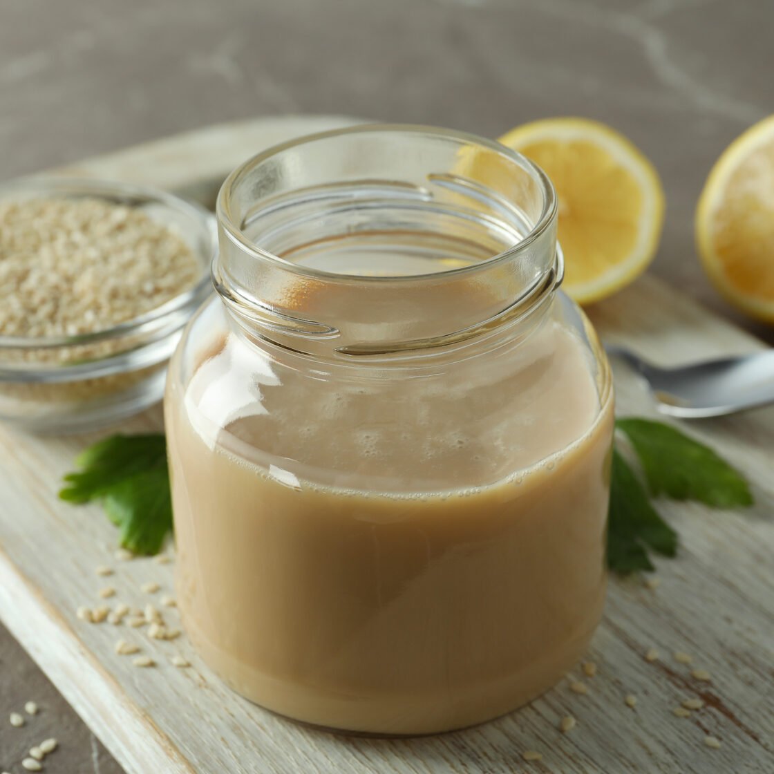 Concept of tasty food with tahini sauce on beige textured background